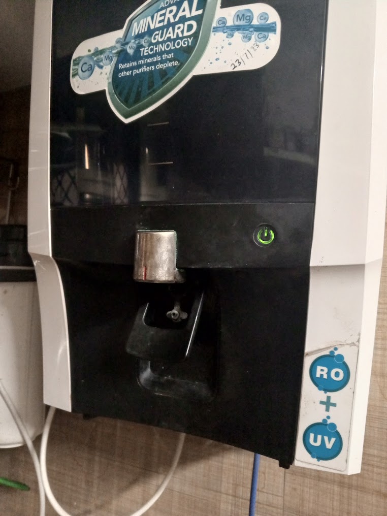 Black and white RO purifier installed on a tiled wall